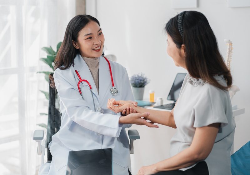 Young Asian Doctor checks the pulse of her patient