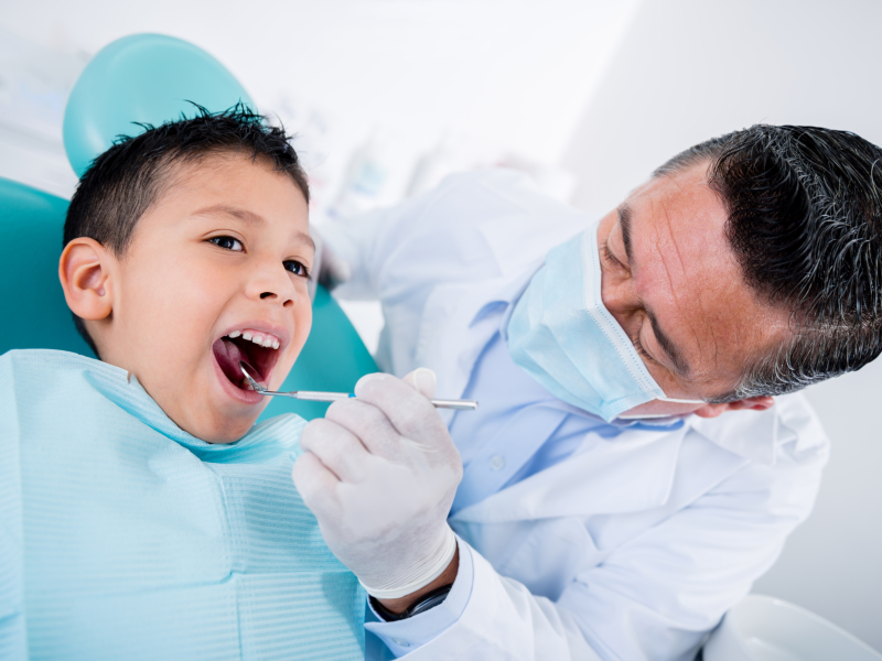 : A dentist applies fluoride varnish to a child’s teeth during a routine visit, supporting cavity prevention and healthy oral development.