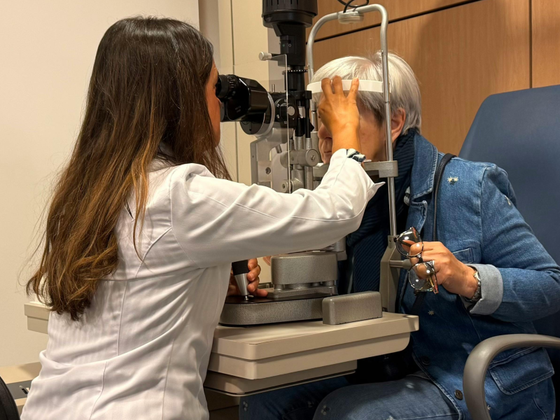 A clinician meets with a patient during an eye appointment, reviewing vision concerns and performing a routine exam.