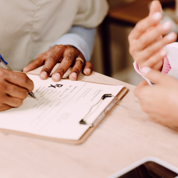 A doctor writes a prescription during a patient visit.